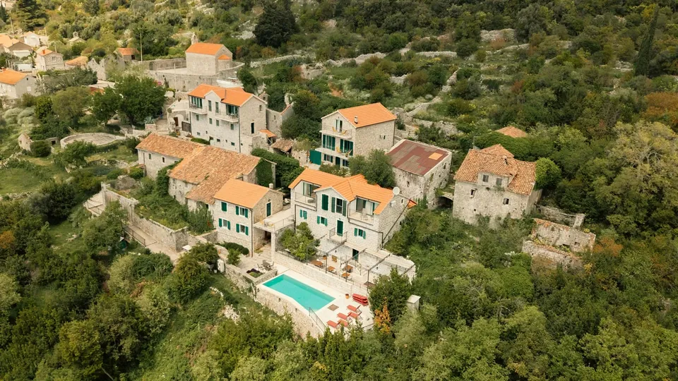 Stone village with terracotta roofs, pool and surrounding macchia