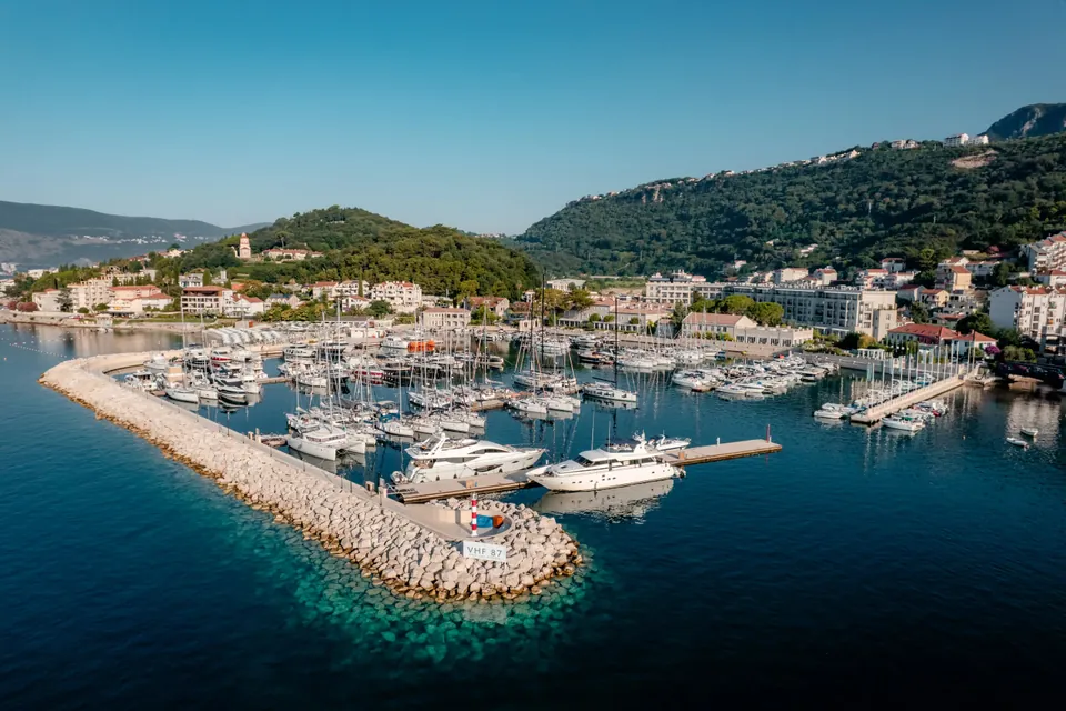 The marina at Meljine from the air, yachts along the pontoons behind the stone breakwater
