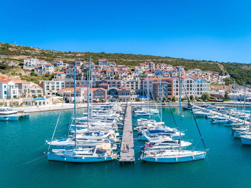 Sailing yachts in marina below stone village houses