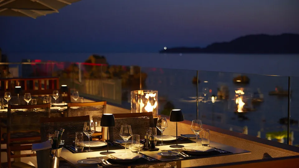 Terrace table with candle lanterns above the dark sea