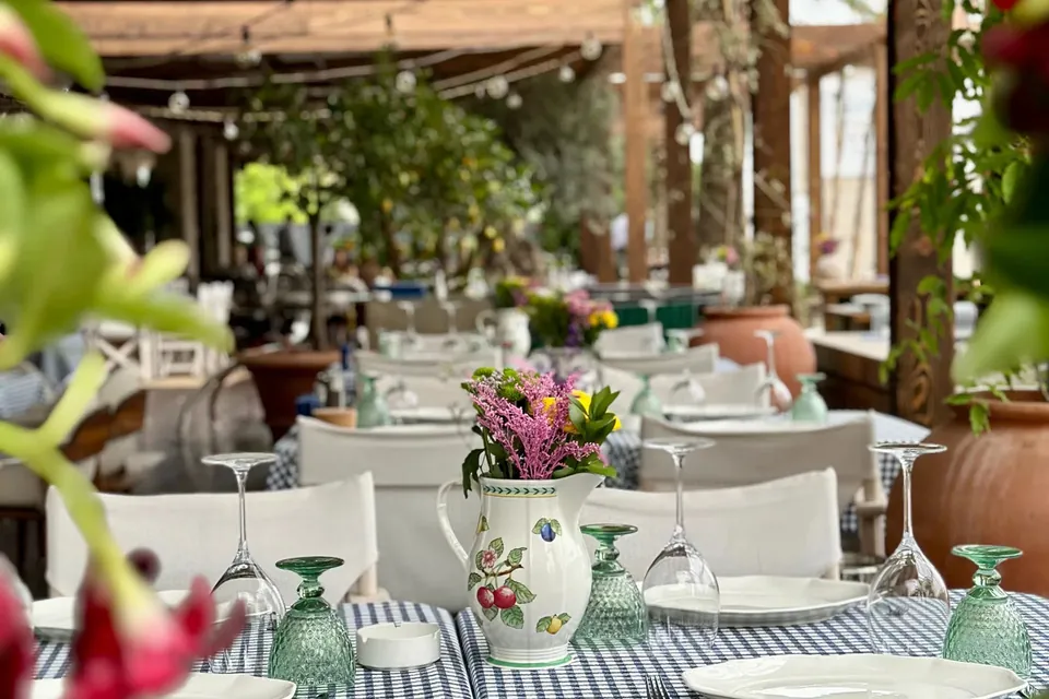 Laid dining table with floral jug and green glasses