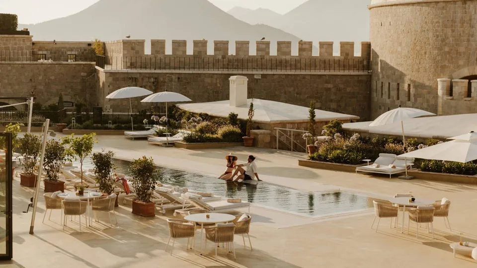 Pool deck within fortress walls, loungers, parasols and crenellated ramparts