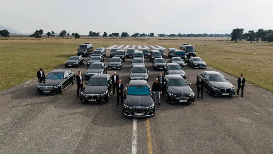 Black chauffeur fleet lined along an airfield with drivers beside vehicles