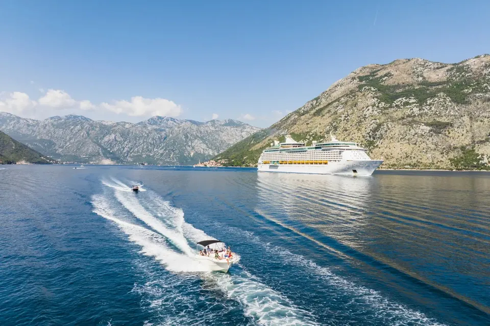 Speedboat crossing Boka Bay near cruise ship and mountains