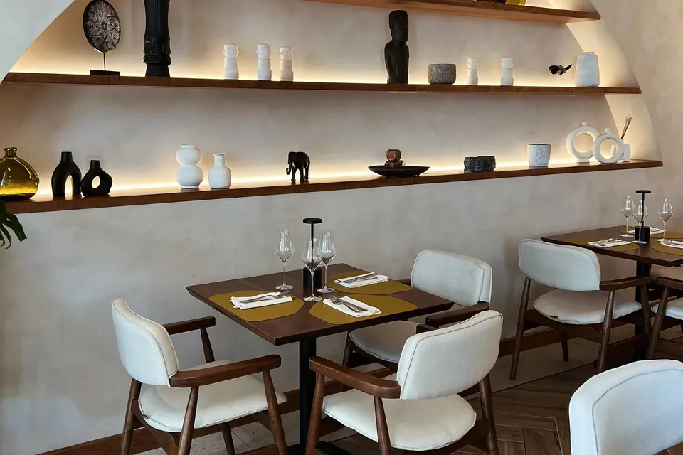 The NOA dining room, lit shelves of ceramics above tables set with linen and glassware