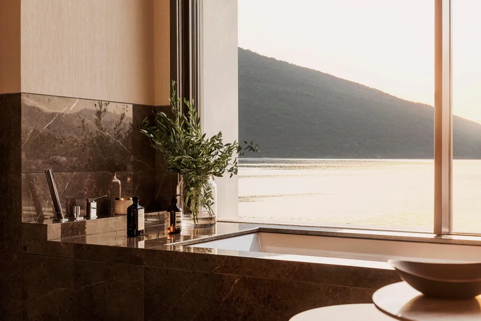 A marble bathroom with the bath set against the window and the bay beyond