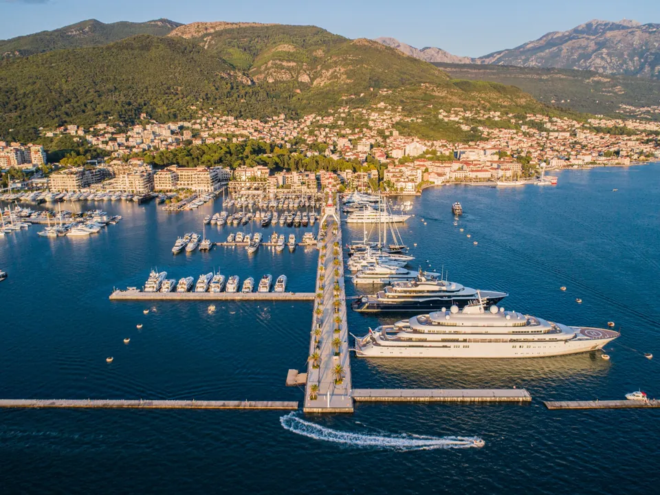 Aerial marina view with superyachts, long jetty and Tivat behind