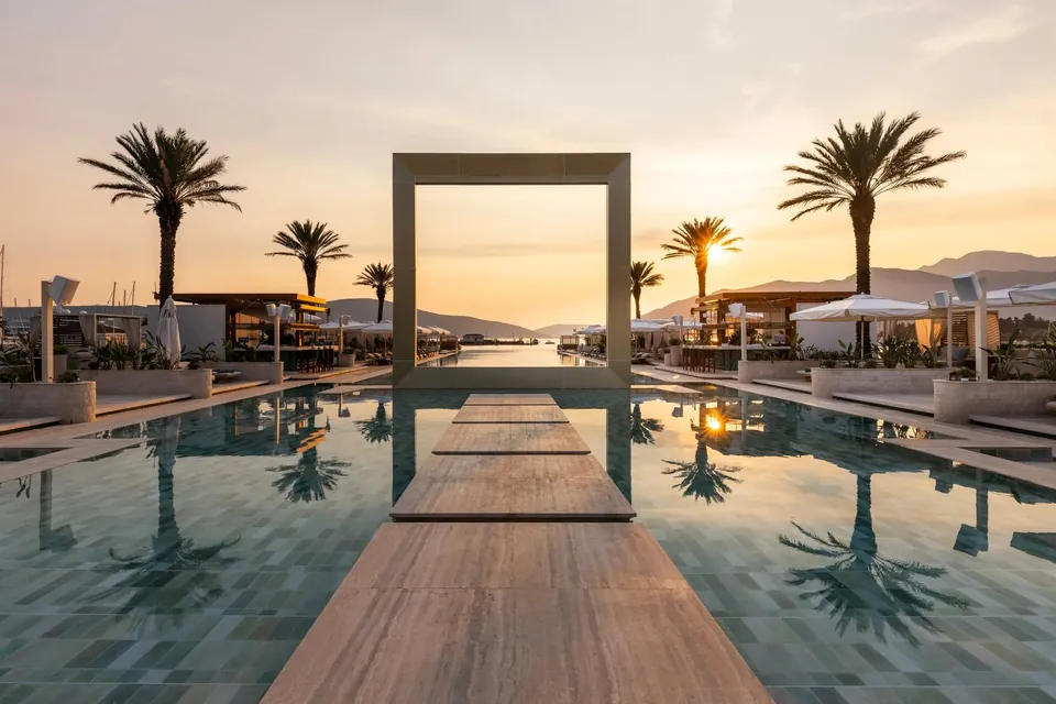 Sunset pool with palms and sculpture beside the water