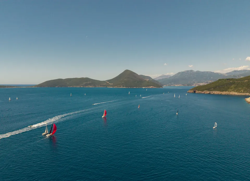 Sailing regatta with red spinnakers across Boka Bay