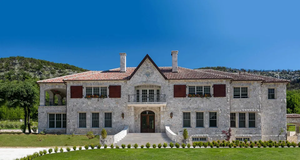 The stone house of the estate seen from the front, with the hillside behind it