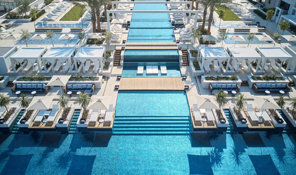 The Pool Club from the air, three pools in line with white cabanas alongside