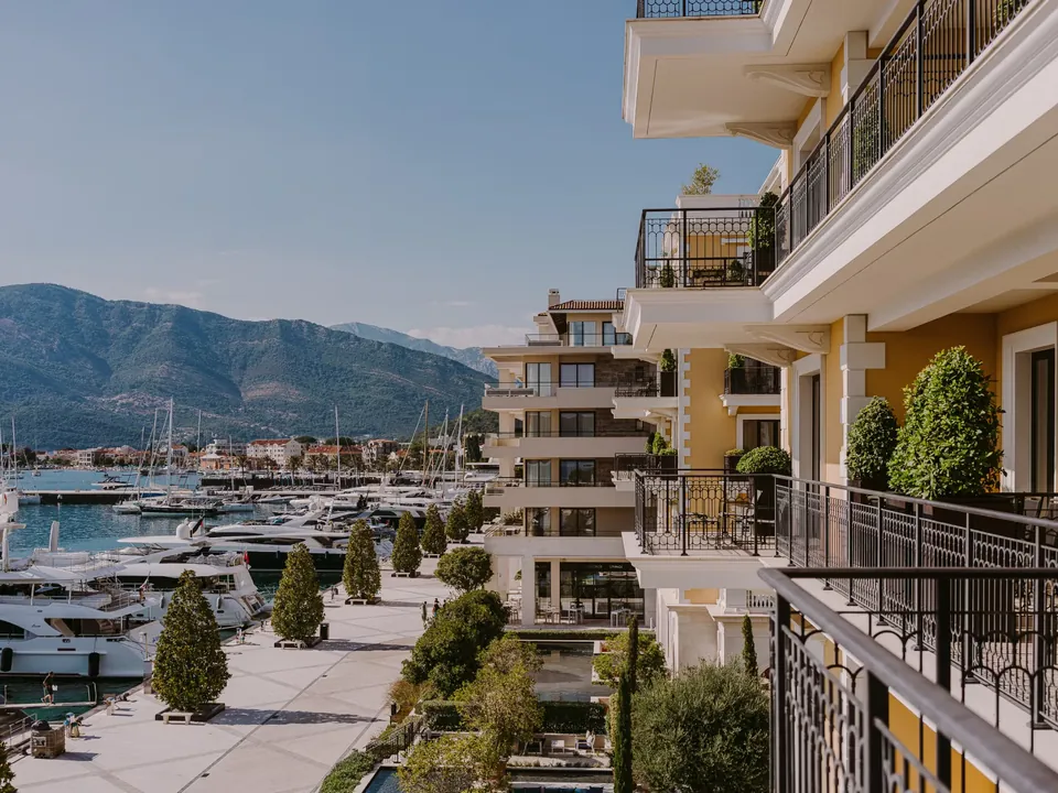 Balconies of the hotel above the marina quay, with superyachts and the hills of Tivat