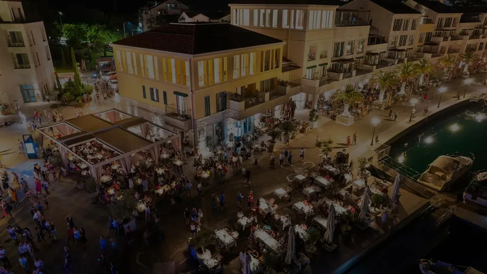The Portonovi marina square at night, seen from above, terraces along the waterfront