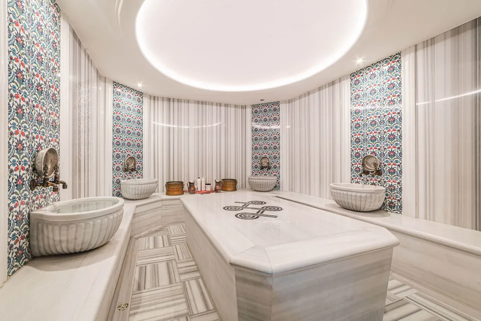 The hammam, a marble navel stone at the centre and carved basins along the walls