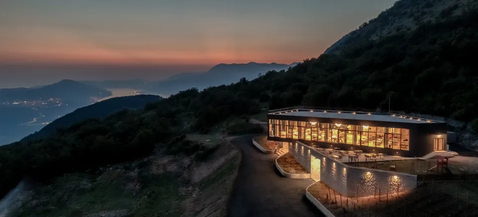 Glazed winery building at dusk above the distant bay