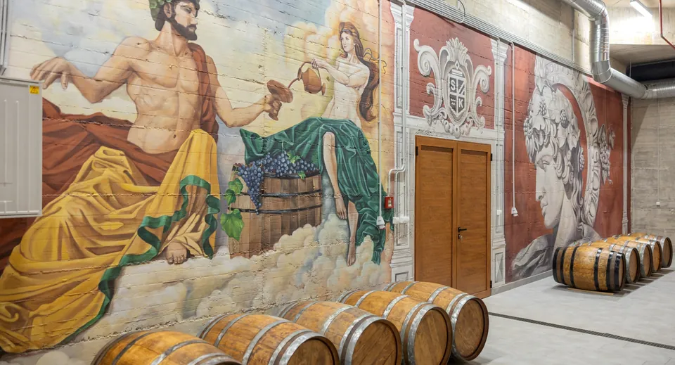 Oak barrels beneath mural of Bacchus and grape gatherer