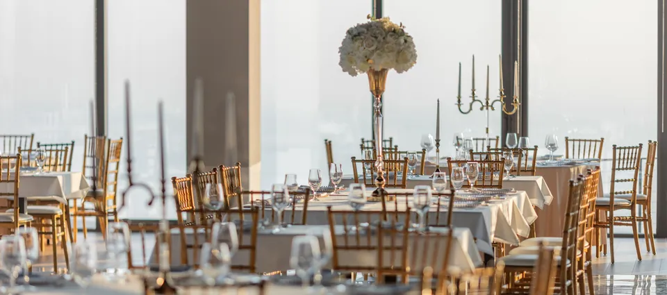 Event hall with white tables, gold chairs and candelabra