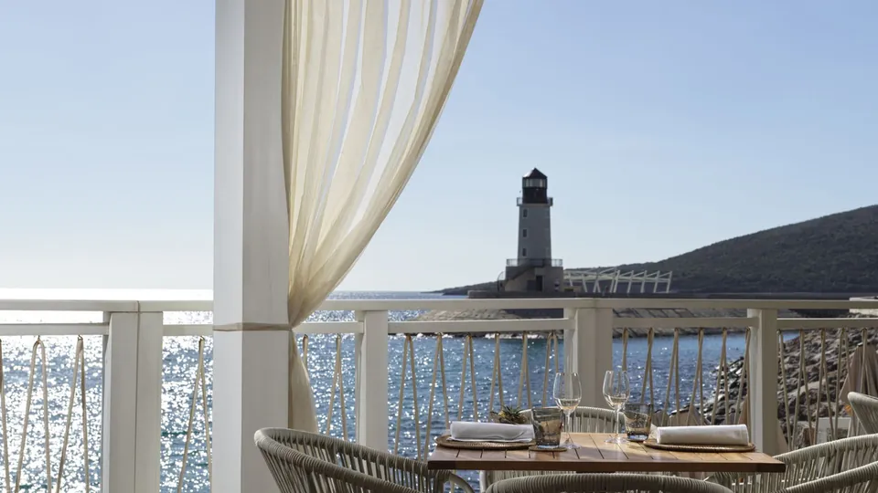 A table set for two on the terrace, the sea and the lighthouse beyond