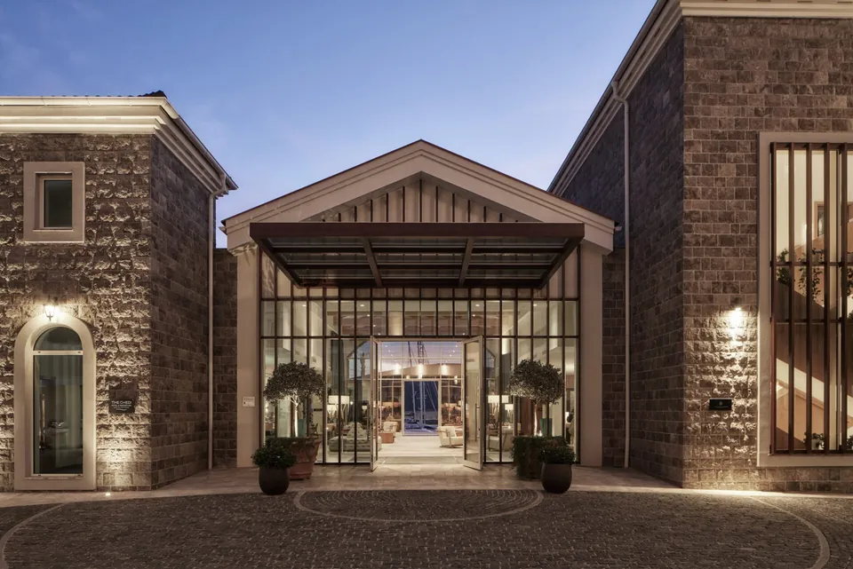 The hotel entrance at dusk, stone walls and a lit glass portal