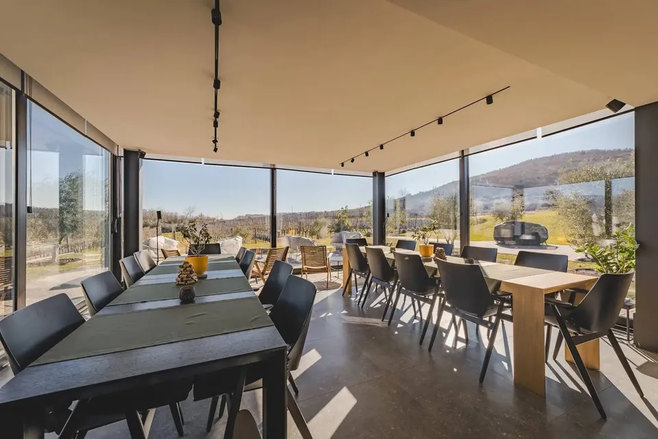 Glass-walled tasting room overlooking vineyard rows and hills