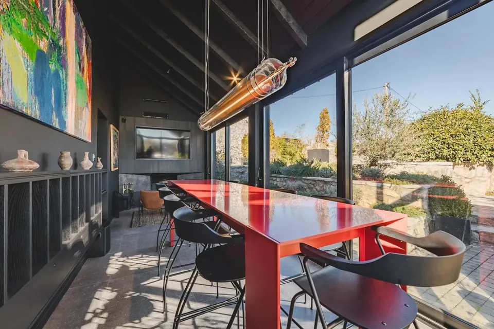 Red steel table and black chairs beneath contemporary paintings