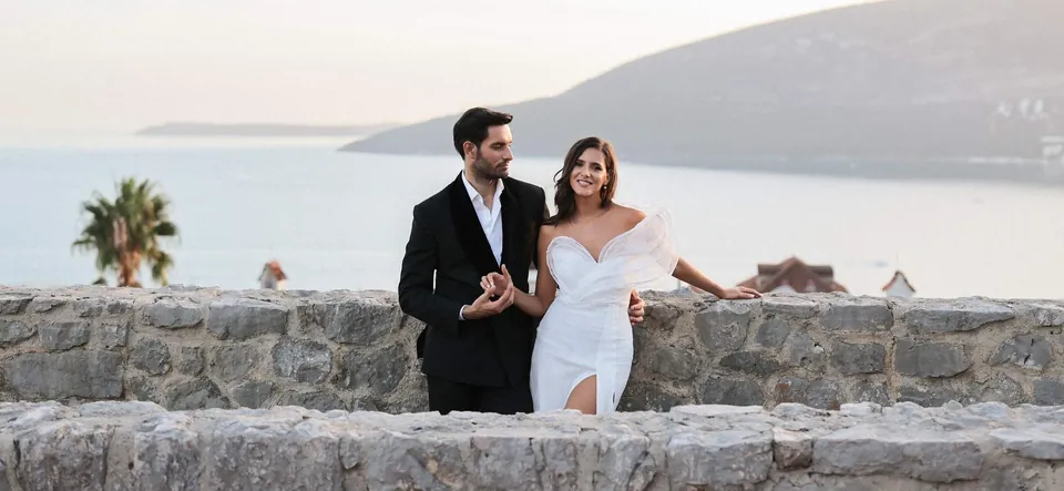 Couple on old stone walls above the sea at dusk